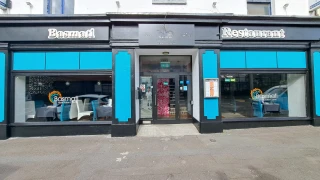 Restaurant exterior with black facade and teal panels around large front windows