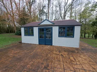 Garden room with grey cladding, blue framed doors and windows on a patio area